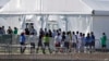 Niños inmigrantes centroamericanos hacen fila para entrar a una casa de campaña en el centro de detención temporal de Homested, Florida. [Foto: Archivo]