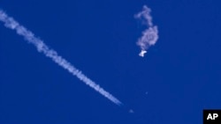 Na fotografiji Čad Fiša, vide se ostaci velikog balona kako padaju ka Atlantskom okeanu, nedaleko od obale Južne Karoline, dok borbeni avion prolazi pored ostavljajući kondenzacijski trag, 4. februara 2023.