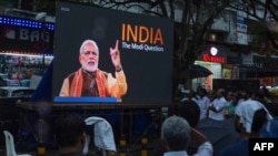 Warga menonton film dokumenter yang ditayangkan BBC "India: The Modi Question", di layar yang dipasang di persimpangan Marine Drive, di Kochi, 24 Januari 2023. (Foto: AFP)