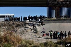 Migran menunggu untuk masuk ke bus pemerintah AS setelah melintasi perbatasan dari Ciudad Juarez, Meksiko, ke El Paso, Senin, 12 Desember 2022. (AP/Christian Chavez)