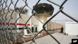 FILE - Guards stand at the entrance of Abu Ghraib prison on the outskirts of Baghdad, Iraq, Feb. 21, 2009. 