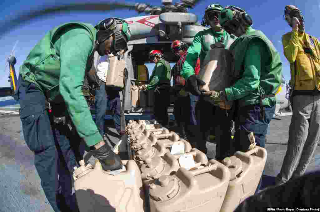 Sailors aboard the U.S. Navy's forward-deployed aircraft carrier USS George Washington load containers of water onto an MH-60S Seahawk, Nov. 15, 2013. (U.S. Navy)
