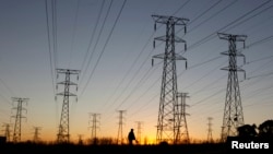 FILE - A man walks past electricity pylons as he returns from work in Soweto, outside Johannesburg, May 15, 2012. 