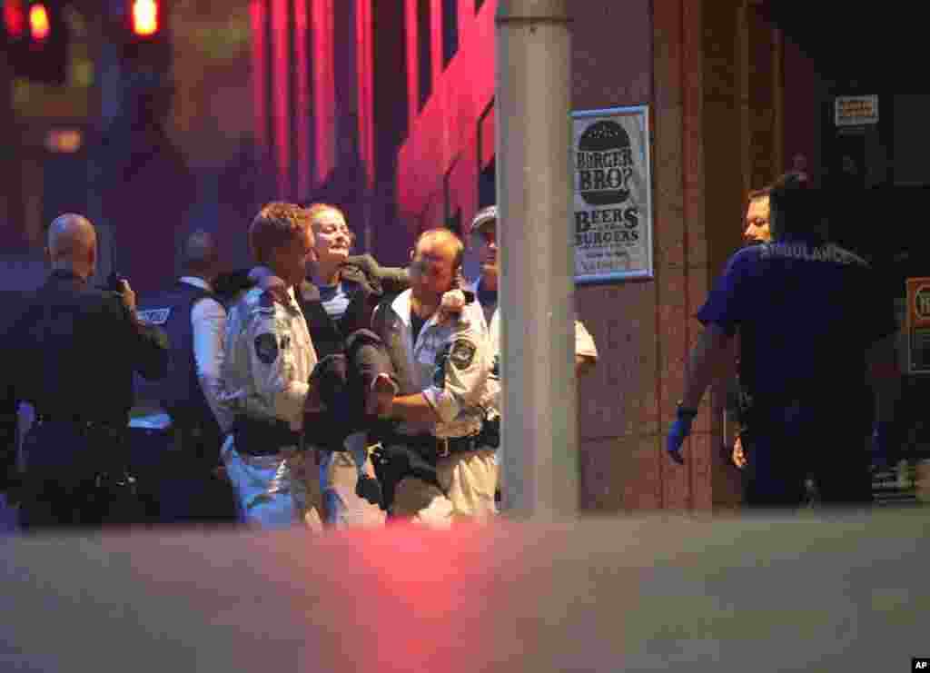 A injured hostage is carried to an ambulance after shots were fired during a cafe siege at Martin Place in the central business district of Sydney, Dec. 16, 2014.