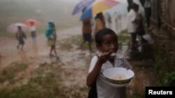 FILE - A student eats his lunch as others wait in a line for their lunch at a school at Letefoho village in Ermera district, March 13, 2012. 