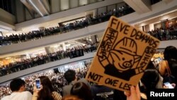 香港抗议者在中环国际金融中心手举“五项诉求，缺一不可”的标语牌大合唱《愿荣光归香港》。