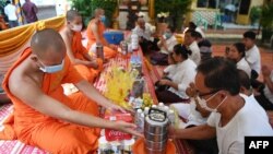 People offer food to Buddhist monks during the Pchum Ben festival (Festival of Death) at a pagoda in Phnom Penh on September 3, 2020. (Photo by TANG CHHIN Sothy / AFP)