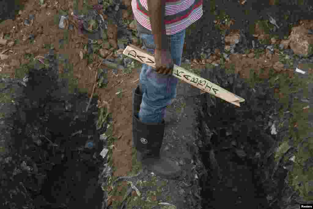 Un fossoyeur tient un écriteau avec le nom d’une victime d’Ebola au cours des funérailles dans un cimetière à Freetown, décembre 17 2014. REUTERS / Baz Ratner