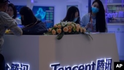 Visitantes a la Feria Internacional China de Comercio de Servicios (CIFTIS) reunidos alrededor de un stand de la firma de tecnología china Tencent el 5 de septiembre de 2020 en Beijing. 