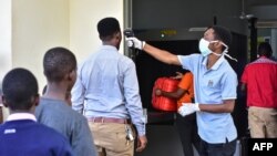 Un travailleur vérifie la température des voyageurs au poste frontière avec le Kenya à Namanga, dans le nord de la Tanzanie, le 16 mars 2020.