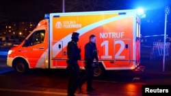 Police officers walk next to an emergency vehicle after a stabbing at the Holocaust memorial in Berlin, Germany, Feb. 21, 2025.