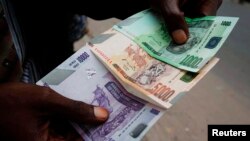 Un commerçant compte des billets de banque congolais à Kinshasa, RDC, 3 juillet 2012.