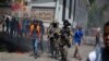 La policía camina entre los manifestantes durante una protesta en la cpaital, Puerto Príncipe, tras el asesinato del presidente de Haití, ocurrido el miércoles 7 de julio de 2021