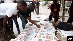 FILE - Men read newspapers with headlines about the Ebola Virus in Lagos, Nigeria. 