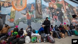 Migrantes comen y esperan ayuda, acampados en una calle del centro de El Paso, Texas, el 18 de diciembre de 2022.