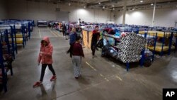 Migrants walk around bunk beds inside a government-run shelter in Ciudad Juarez, Mexico, on Sunday, Dec. 18, 2022. (AP Photo/Andres Leighton)