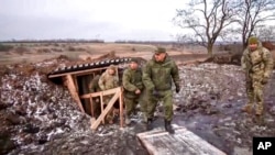 FILE - Russian Defense Minister Sergei Shoigu, center, walks out of a trench, escorted by a group of officers as he inspects Russian troops at an undisclosed location in Ukraine, Dec. 22, 2022, in this photo taken from video released by Russian Defense Ministry Press Service.