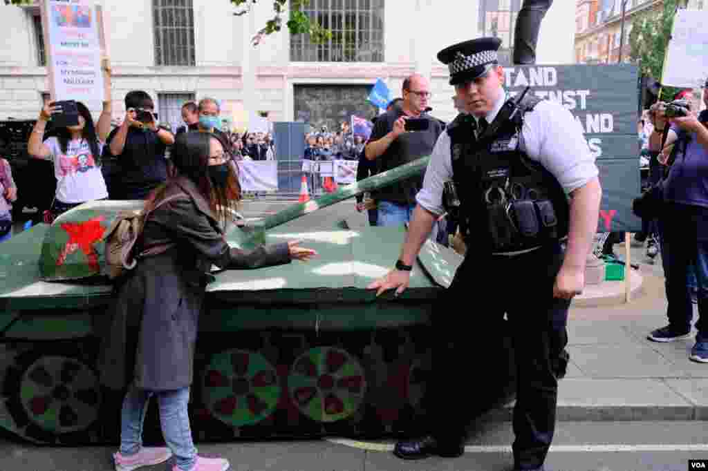 示威者把紙紮坦克擺在中國駐英大使館外並企圖移動,但被在場警察按下。(美國之音鄭樂捷)