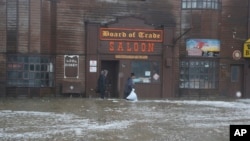 Two men walk through rushing water on Front Street, just a half block from the Bering Sea, in Nome, Alaska, Sept. 17, 2022. 