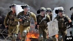 Pasukan keamanan Israel berlari ke arah demonstran Palestina selama bentrokan menyusul protes terhadap pengambilalihan tanah Palestina oleh Israel di desa Kfar Qaddum di Tepi Barat (23/9). 
