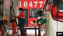 FILE - Petrol station attendants fill up vehicles at a petrol station in Hong Kong on March 7, 2022 with fuel prices rising as traders fretted over the fallout from Russia's invasion of Ukraine. (Photo by Peter PARKS / AFP)