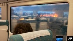 Pasajeros de un tren toman fotos de un incendio forestal en Zamora, España, el lunes 18 de julio de 2022. (Foto AP/Francisco Seoane Pérez)