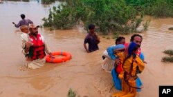 Para petugas penyelamat mengevakuasi sejumlah warga desa yang menjadi korban banjir di Lasbella, sebuah distrik di wilayah barat daya Pakistan, pada 26 Juli 2022. (Foto: AP/Hamdan Khan)