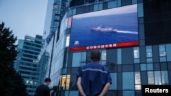 北京市民在观看街头电子屏幕上官媒央视播放的中国军队在台湾附近举行实弹军演的报道。（2022年8月4日）