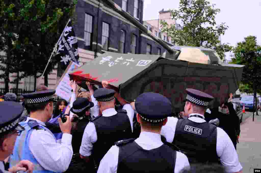 2022年6月4日,倫敦警察在中國駐英國大使館外阻止示威者抬著的紙紮坦克走近大使館範圍。(美國之音鄭樂捷)