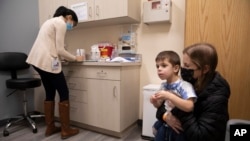 FILE - Ilana Diener holds her son, Hudson, 3, during an appointment for a Moderna COVID-19 vaccine trial in Commack, N.Y., on Nov. 30, 2021. 