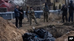 People stand next to a mass grave in Bucha, on the outskirts of Kyiv, Ukraine, April 4, 2022.