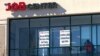 FILE - A man walks past the signs of an employment agency, in Manchester, New Hampshire, March 2, 2021. 