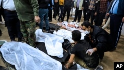 一名男子坐在2024年1月3日伊朗克爾曼恐怖爆炸中喪生親人的屍體旁邊，另外一人在安慰他。（美聯社照片）
