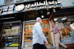 FILE - People walk past by a Syrian jewelry shop in Istanbul's Kucukcekmece district, Turkey, July 5, 2019.