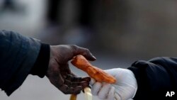 Una mujer que trabaja para una organización social entrega un refrigerio a un vagabundo en la Avenida 9 de Julio en Buenos Aires, el lunes 31 de mayo de 2021.