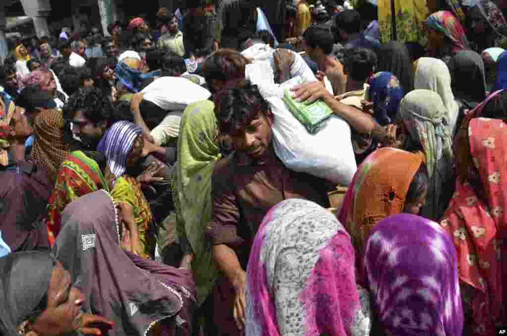 Victims of the unprecedented flooding from monsoon rains carry relief aid, in Jaffarabad, a district of Pakistan's southwestern Baluchistan province, Sept. 4, 2022.