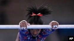 Simone Biles, de Estados Unidos, se ejercita en las barras asimétricas durante las calificaciones de gimnasia artística femenina en los Juegos Olímpicos de Tokio, el 25 de julio de 2021, en Tokio.