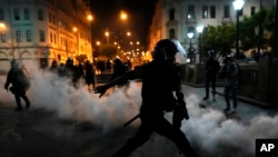 Una nube de gases lacrimógenos envuelve a los policías que intentan disipar a simpatizantes del destituido presidente Pedro Castillo, el domingo 11 de diciembre de 2022, en la plaza San Martín, en Lima.
