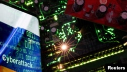 АРХИВА - Илустрација на која е напишано „Cyberattack“ и кодови на мобилен телефон поставен до матична плоча од компјутер, илустрацијата е направена на 23 февруари 2023 година.