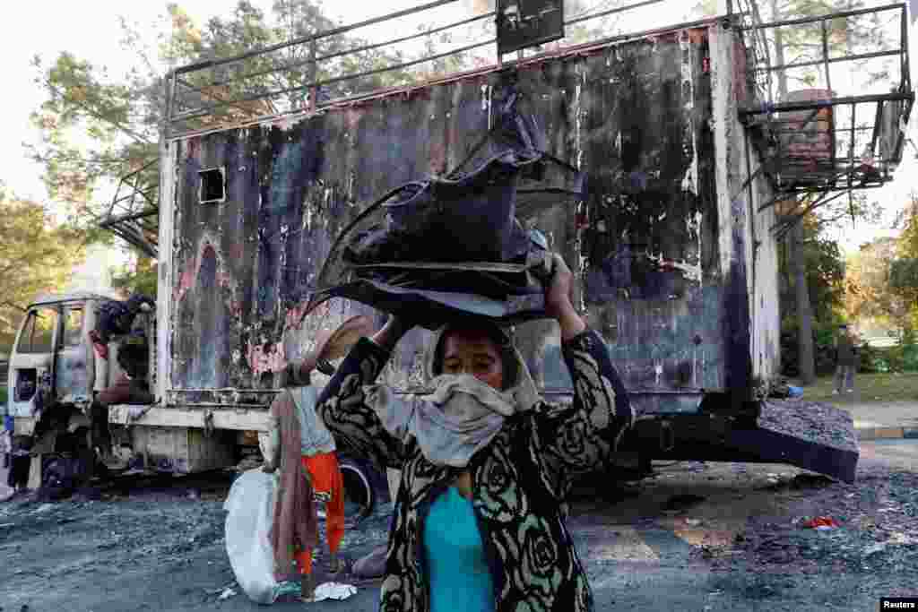 A woman carries recyclables from the burnt truck used by Bushra Bibi, wife of jailed former Pakistani Prime Minister Imran Khan, after security forces launched a raid on supporters of Khan's party Pakistan Tehreek-e-Insaf (PTI) who had stormed the capital demanding his release on Nov. 26, 2024, in Islamabad. 
