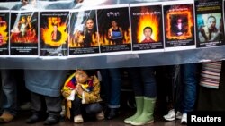 A child gestures at the feet of protesters holding a sign commemorating victims of self-immolation during a solidarity march from the Chinese Consulate to the United Nations (UN) Headquarters in support of Tibet in New York, December 10, 2012.