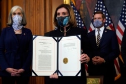 La presidenta de la Cámara de Representantes, Nancy Pelosi, muestra el artículo de juicio político firmado contra el presidente Donald Trump en una ceremonia antes de transmitirlo al Senado para su juicio el 13 de enero de 2021.