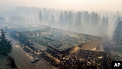 
Asap membubung dari bekas-bekas Old Town Plaza yang hangus terbakar kebakaran lahan di Kota Paradise, California, 15 November 2018.