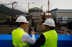 FILE - British and Chinese officials talk near a nuclear reactor under construction in Taishan, Guangdong province, Oct. 17, 2013. Britain has allowed Chinese companies to take majority stakes in nuclear power projects in the country.