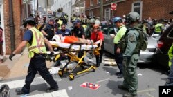 Rescue personnel help injured people after a car ran into a large group of protesters after an white nationalist rally in Charlottesville, Va., Aug. 12, 2017. 