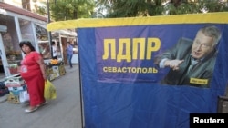 Seorang wanita berjalan melewati sebuah poster kampanye pemilihan Vladimir Zhirinovsky, pemimpin partai Rusia Liberal Demokrat, menjelang pemilihan parlemen 18 September di pelabuhan Laut Hitam dari Sevastopol, Krimea, 16 September 2016. (REUTERS/Pavel Rebrov).