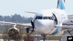Un homme sort de l'avion détourné d'Egyptair depuis la fenêtre du cockpite à l'aéroport de Larnaca à Chypre le 29 mars 2016.