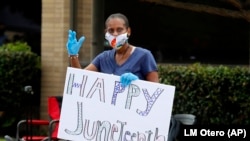 Une femme fait signe de la main lors d'une célébration du 19 juin à Dallas, le vendredi 19 juin 2020. 