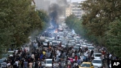 En esta foto del 21 de septiembre de 2022 tomada por un individuo que no es empleado de Associated Press y obtenida por AP fuera de Irán, los manifestantes bloquean una calle durante una protesta por la muerte de una mujer que fue detenida por la policía moral del país.
