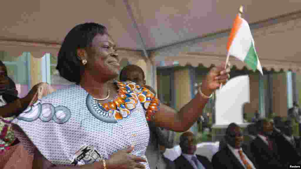 Simone Gbagbo, l'épouse du président Laurent Gbagbo de Côte-d'Ivoire, agite un drapelet, saluant la foule au cours de la cérémonie d'ouverture des célébrations marquant le 50e anniversaire de l’indépendance du pays, au palais présidentiel, à Abidjan, 31 janvier 2010.